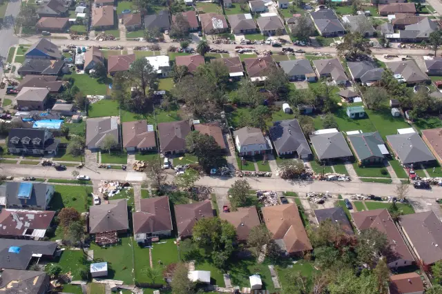 Storm-damaged home with blue tarp covering missing roof sections in the aftermath of a hurricane
