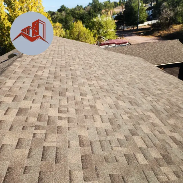 Aerial drone view of a light tan dimensional asphalt shingle roof on a residential home in a wooded neighborhood