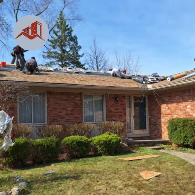 Roofing crew tearing off shingles on a single-story red brick ranch home with mature shrubs