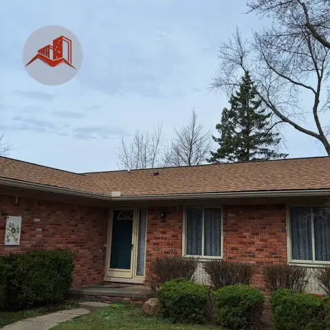 Single-story red brick ranch home with a finished tan dimensional asphalt shingle roof