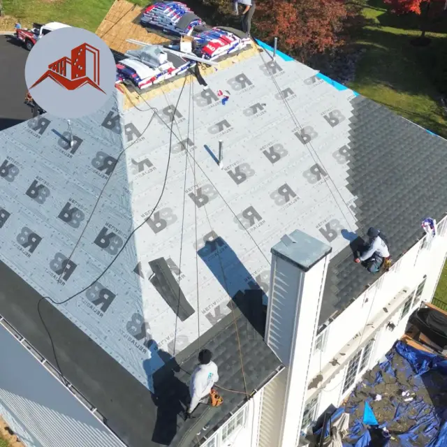 Aerial drone view of a complex hip roof with synthetic underlayment fully installed and crew preparing to lay shingles