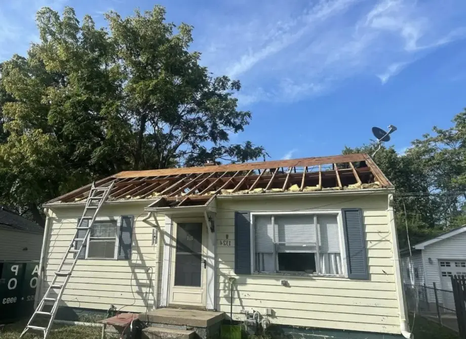 Single-story bungalow with full roof tear-off down to the rafters showing exposed framing during a roof replacement