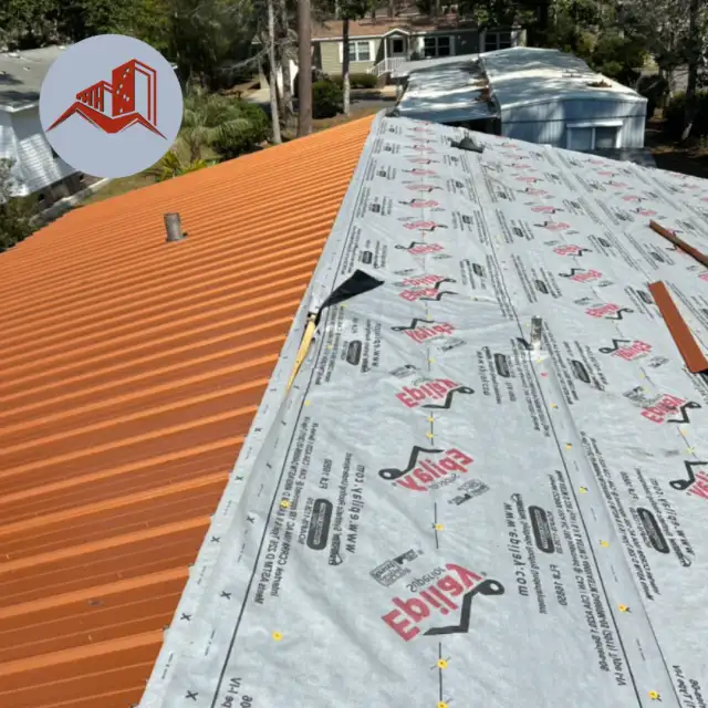 Orange ribbed metal roofing panels being installed over synthetic underlayment on a residential home