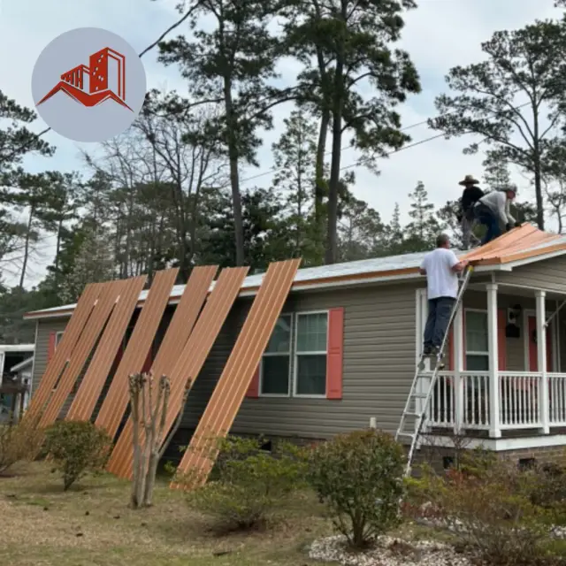 Crew installing copper-toned ribbed metal panels on a manufactured home with new panels stacked nearby