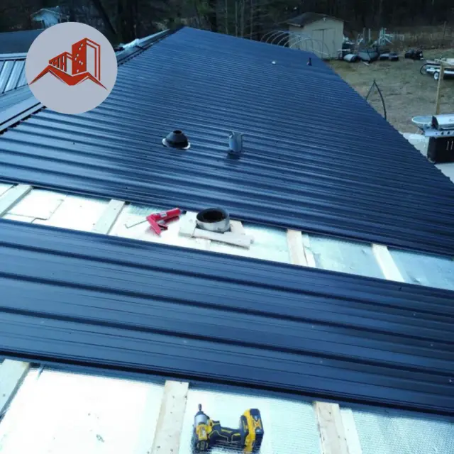 Overhead view of a partially installed dark navy ribbed metal roof showing exposed wood furring strips