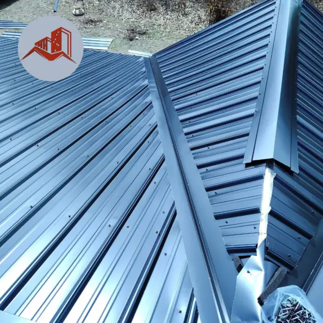 Close-up of a finished dark blue-gray standing seam metal roof with sharp ridge line on a residence