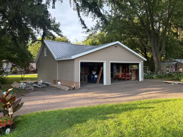 Detached two-car garage after new tan siding and gray metal roof installation