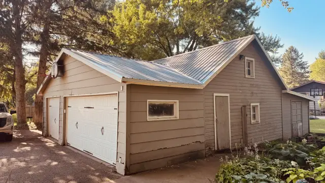 Two-car garage with a new gray ribbed metal roof and white carriage-style doors