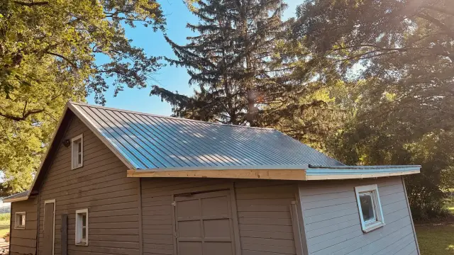 Outbuilding with a freshly installed ribbed metal roof and new fascia boards