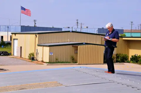 Inspector photographing hail-damaged asphalt shingle roof for storm damage claim documentation