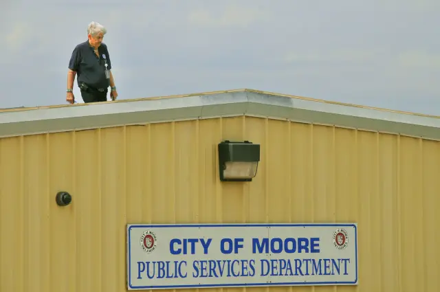 Inspector surveying widespread hail damage on a flat roof after a severe storm